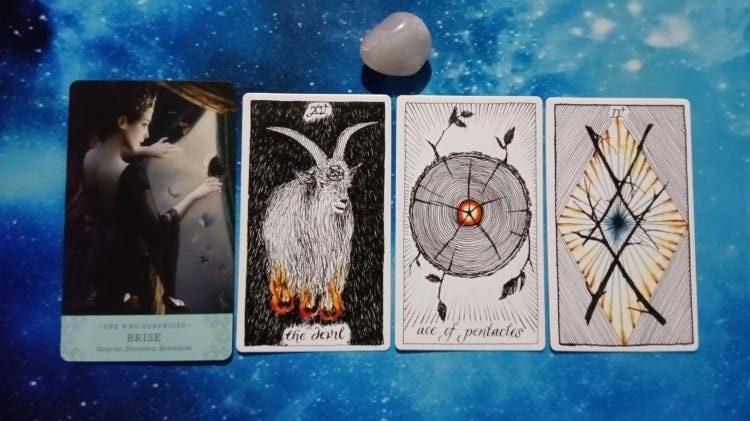 Elle Qui and Wild Unknown Tarot cards with pink stone on starry blue background