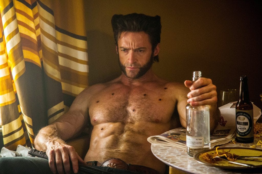 A shirtless Wolverine sits at a table holding a liquor bottle, fresh bullet wounds visible across his chest. A shirtless Wolverine sits at a table holding a liquor bottle, fresh bullet wounds visible across his chest.