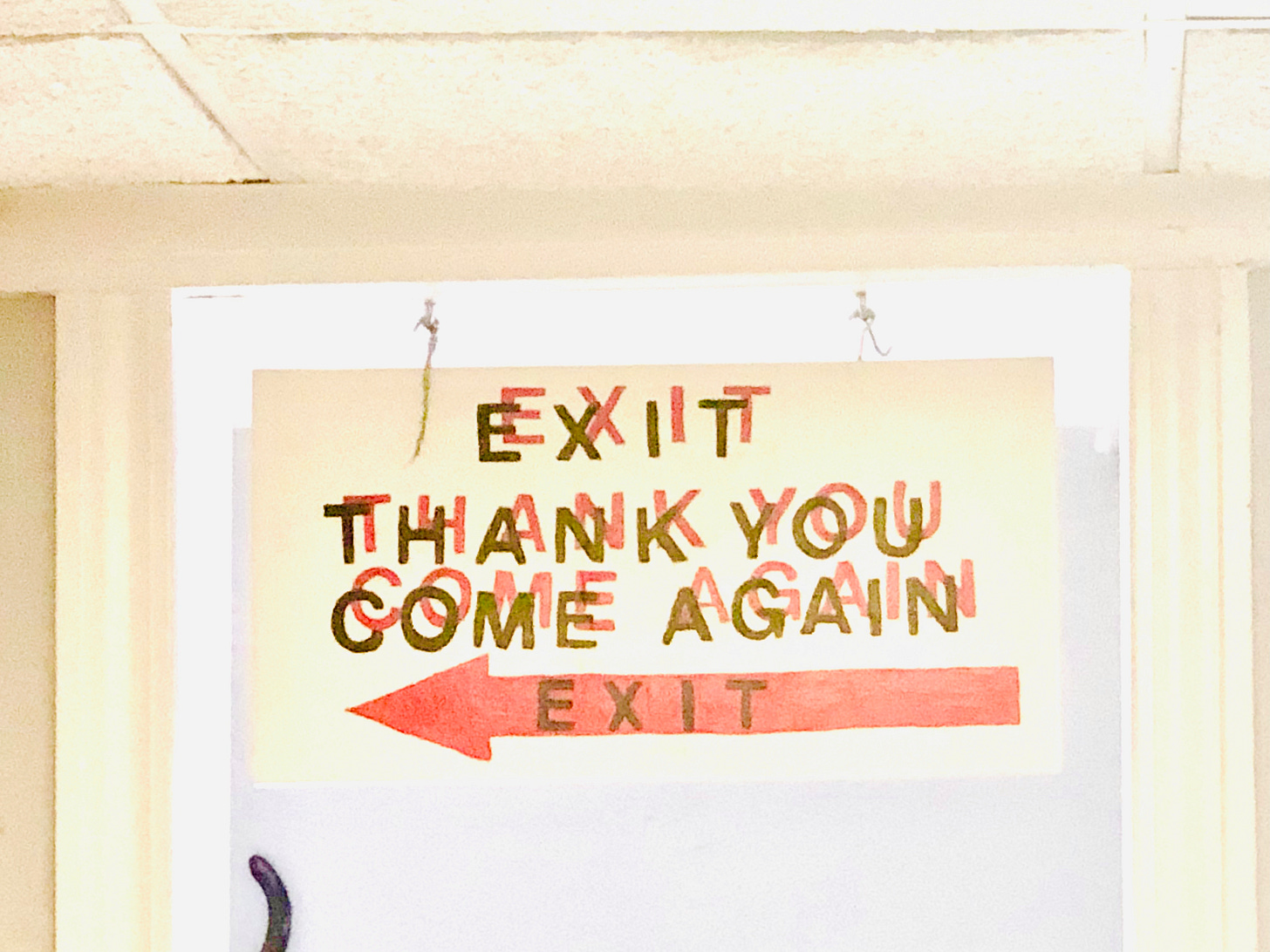 an over-exposed photo of a screenprinted sign that says EXIT THANK YOU COME AGAIN with a red arrow pointing to the exit