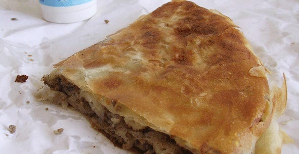 A closeup of a flakey piece of burek. A closeup of a flakey piece of burek.