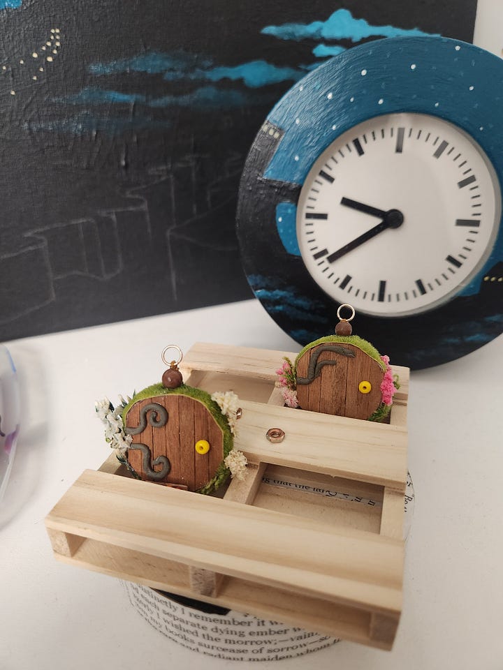 Acrylic painting of a bottle and hobbit door earrings crafted from salvaged materials