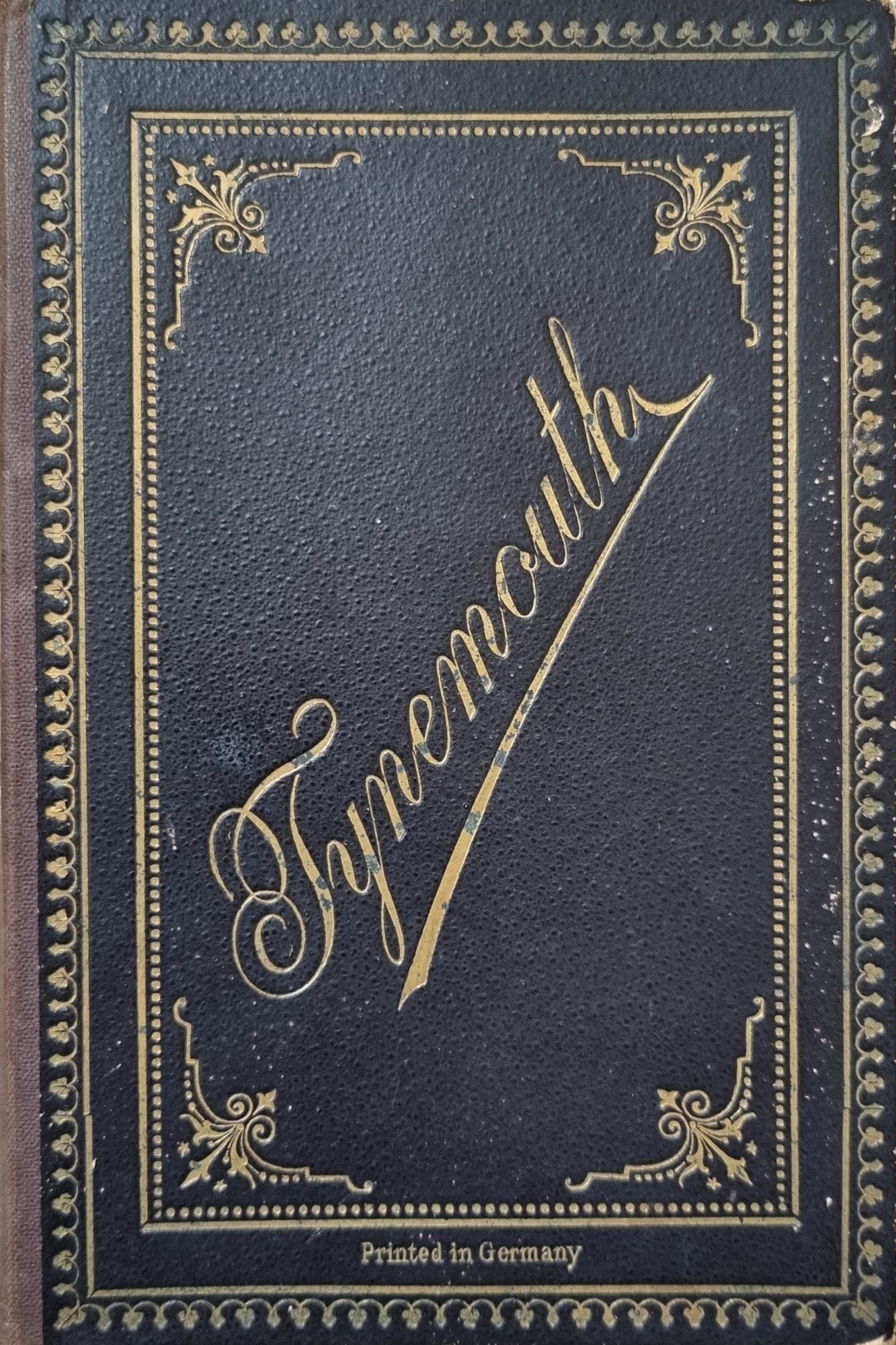 Close-up of a decorative black book cover embossed with gold lettering that reads 'Tynemouth,' featuring ornate designs and the text 'Printed in Germany.'