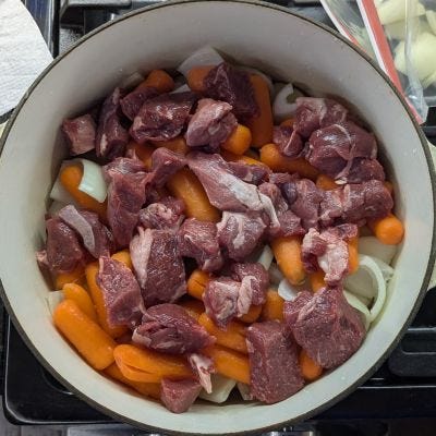Picture of first potatoes, then onions, then carrots and meat in the pot