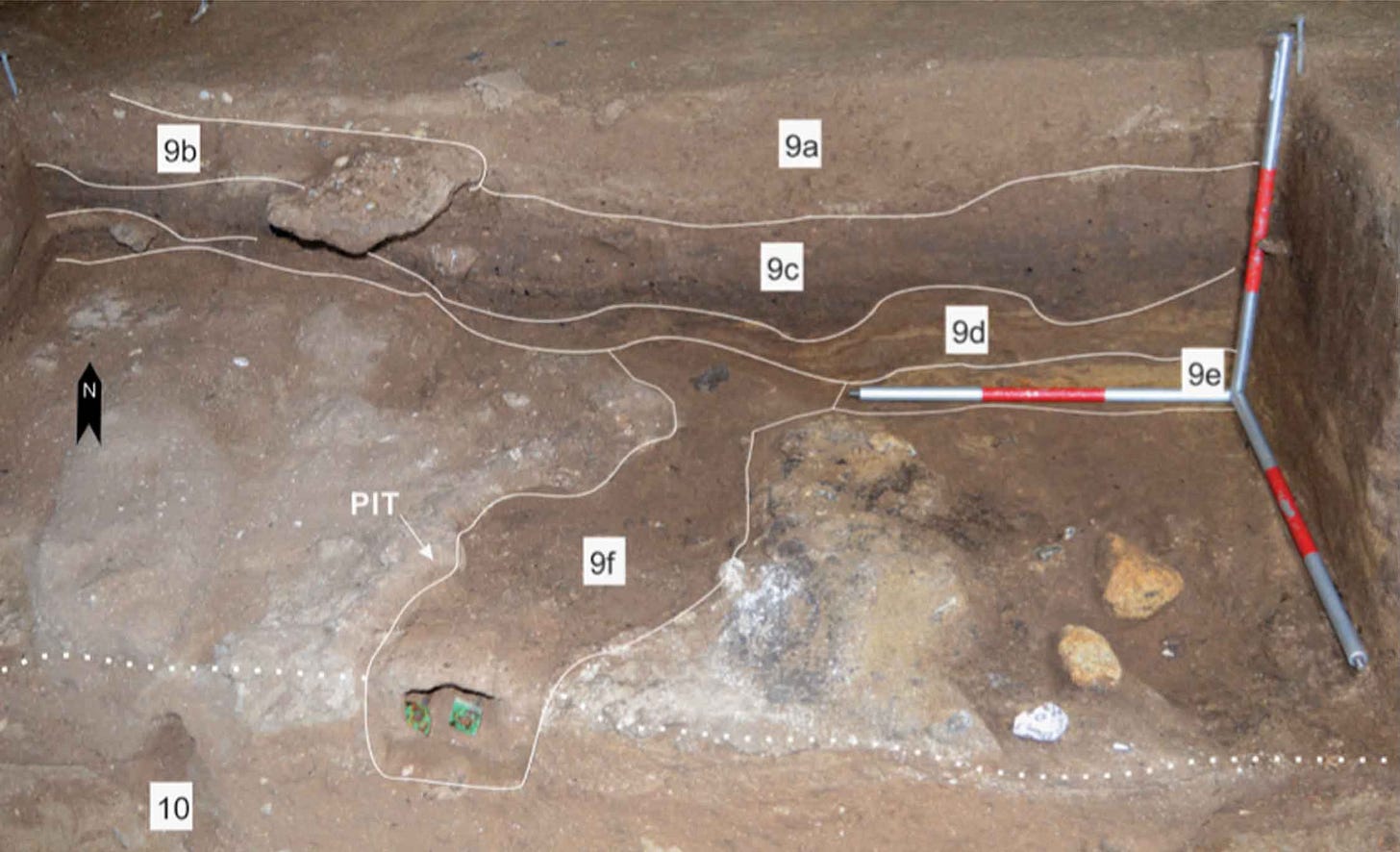 Excavation photo showing a pit structure and charcoal area with rocks visible