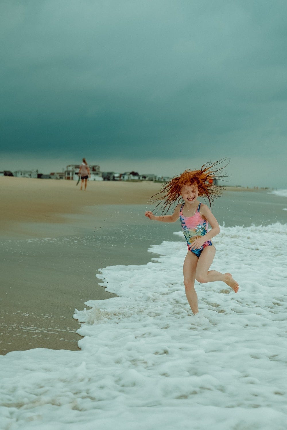 woman in white bikini walking on white sand beach during daytime