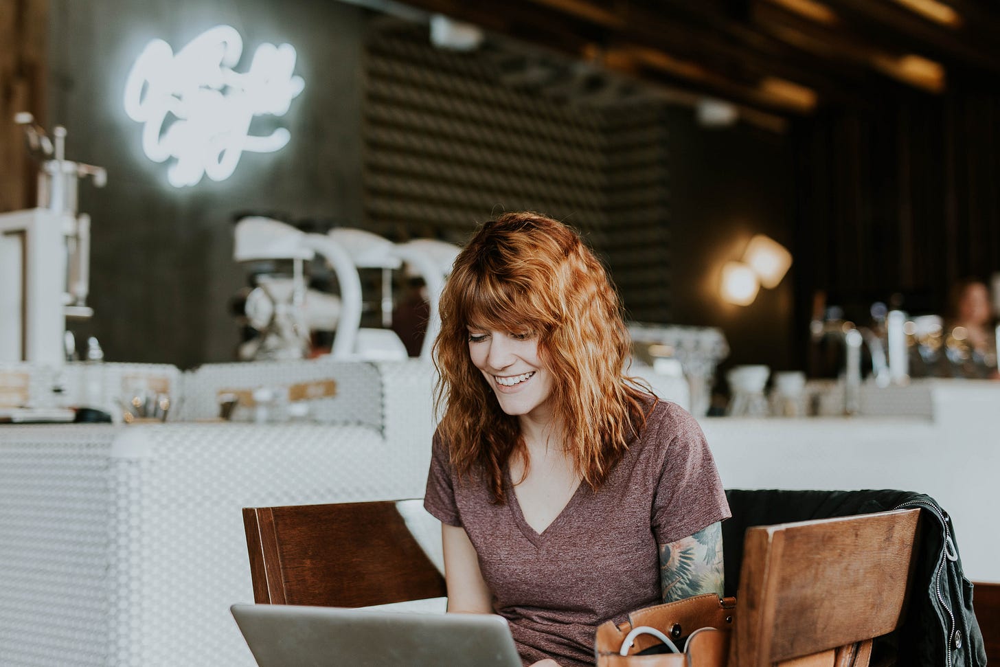 person smiling into a laptop at a coffee shop person smiling into a laptop at a coffee shop