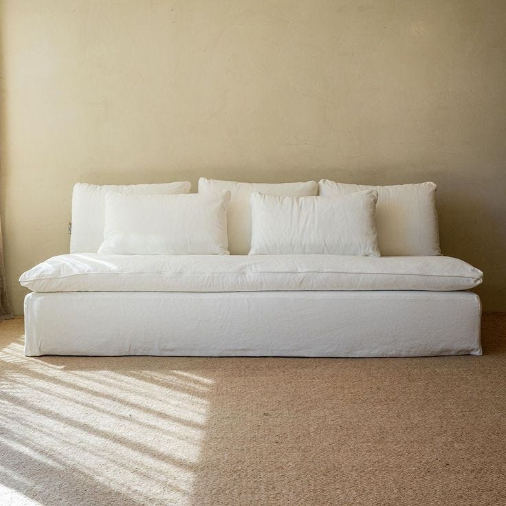 This may contain: a white couch sitting in the middle of a living room next to a window with curtains