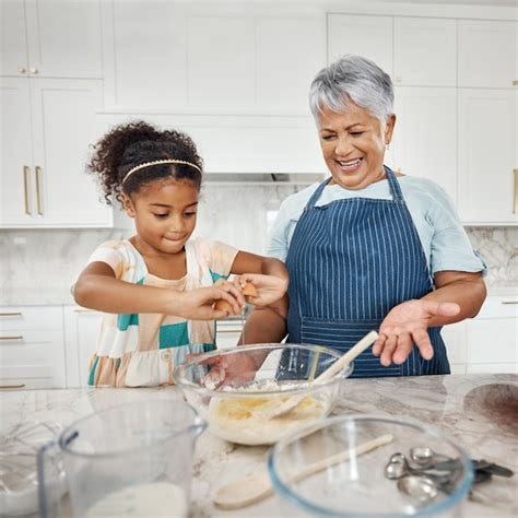 Premium Photo | Learning cooking grandmother and girl with egg and flour in bowl in home kitchen ...