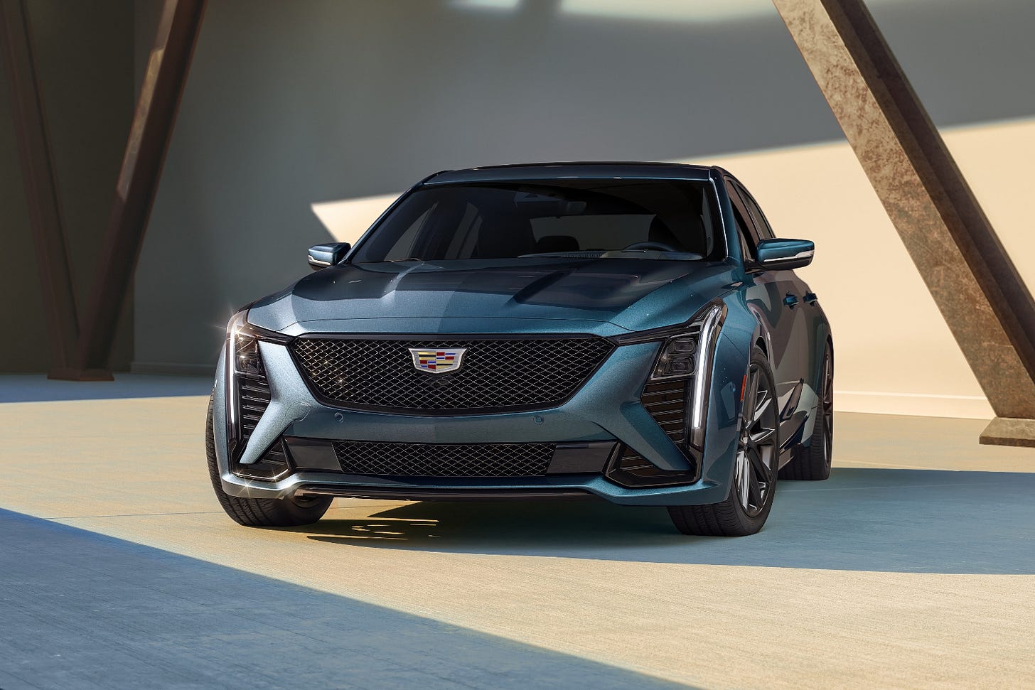 A blue 2025 Cadillac CT5 is parked near a wall decorated with wood beams.