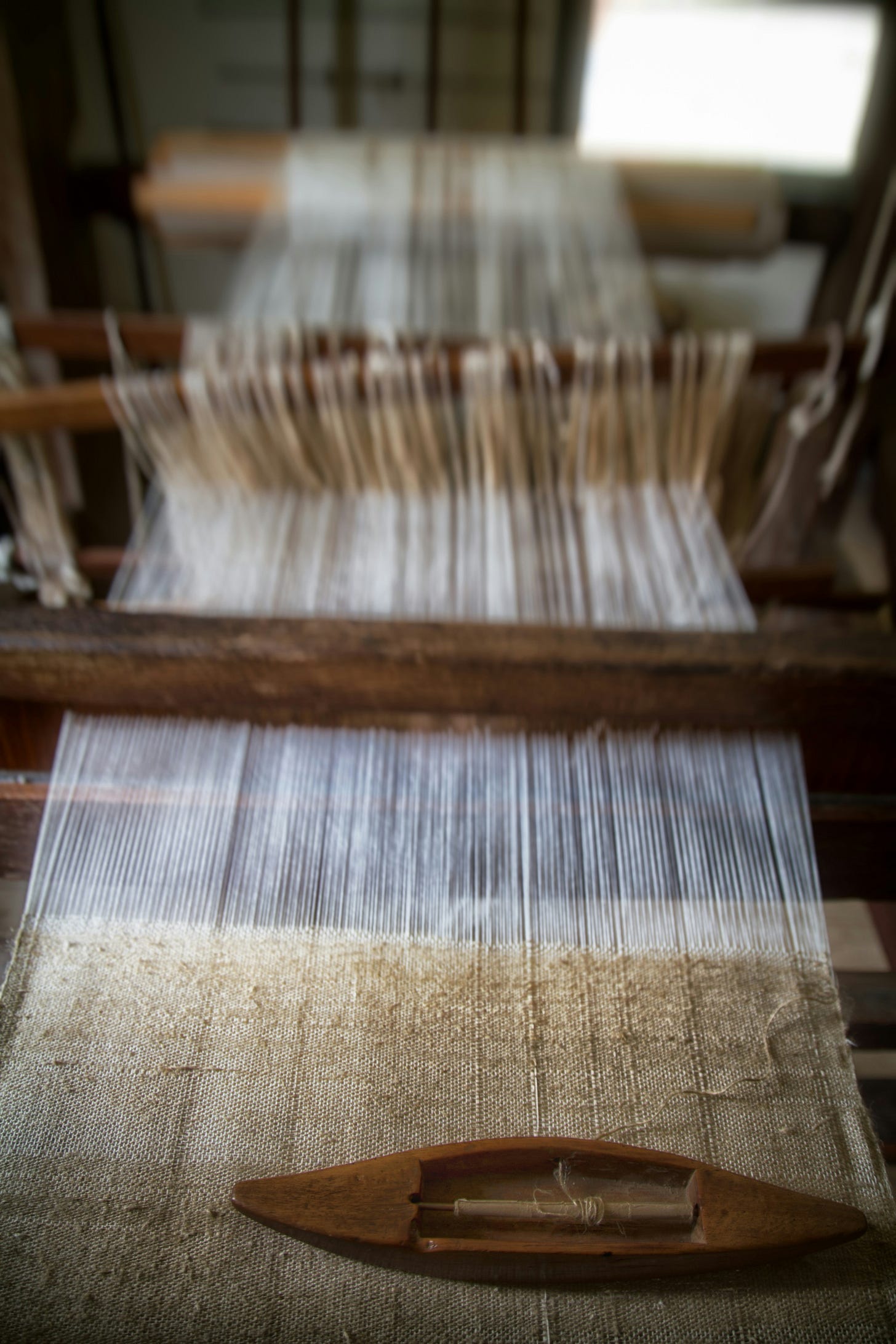 a loom with white cotton fabric being woven.