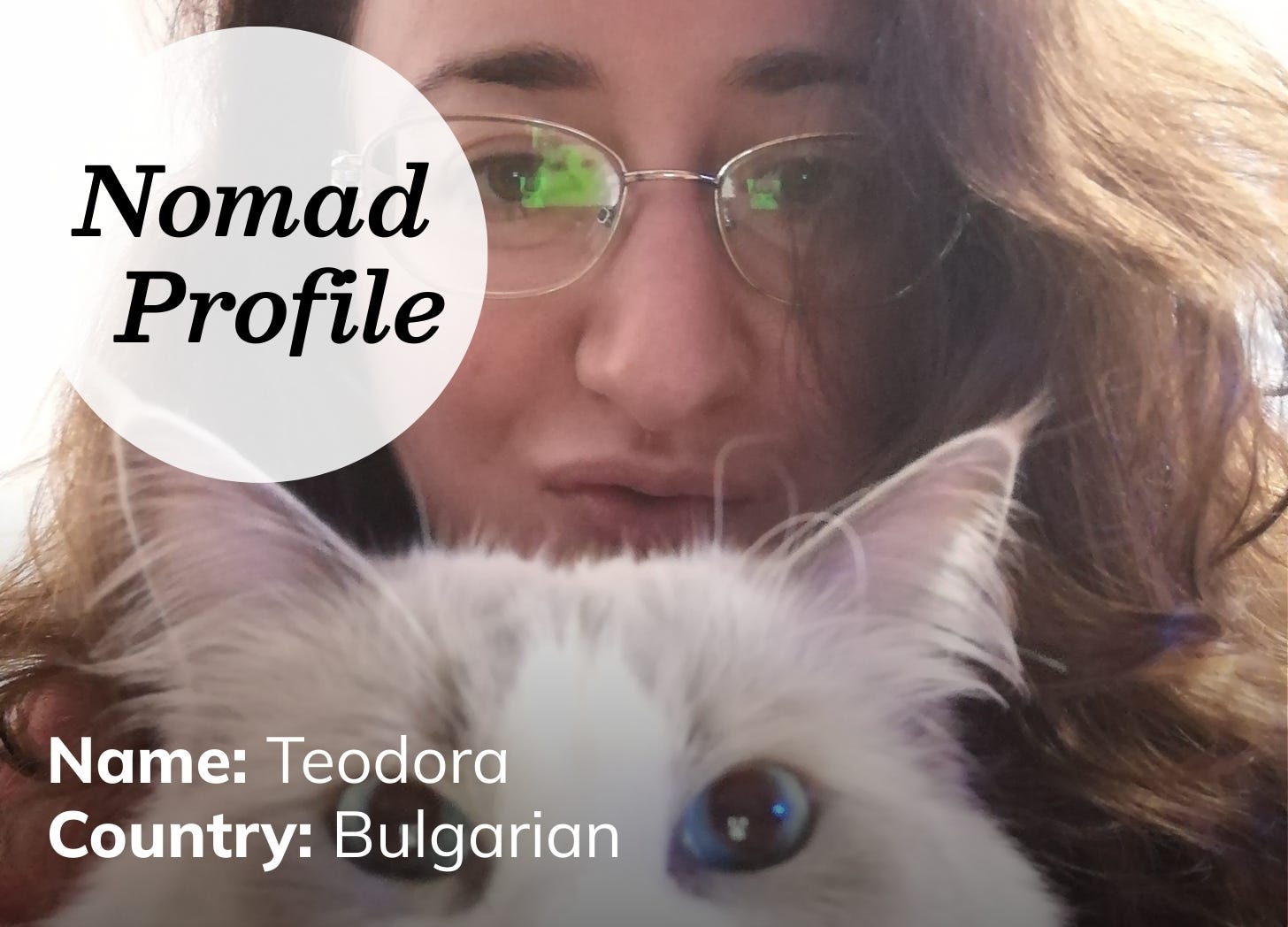 A white woman with wavy brown hair and gold-rimmed glasses holds a fluffy, white cat up in front of her face. 