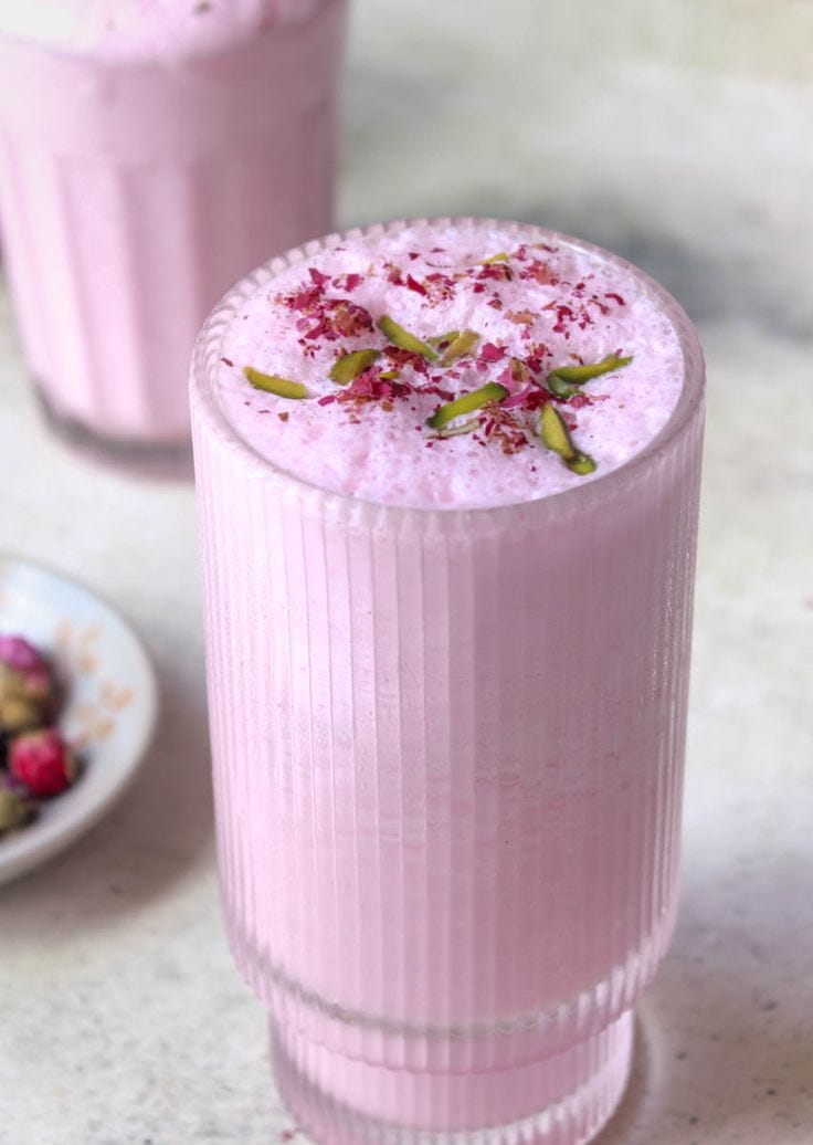 This contains: Rose lassi garnished with dried rose petals and pistachios