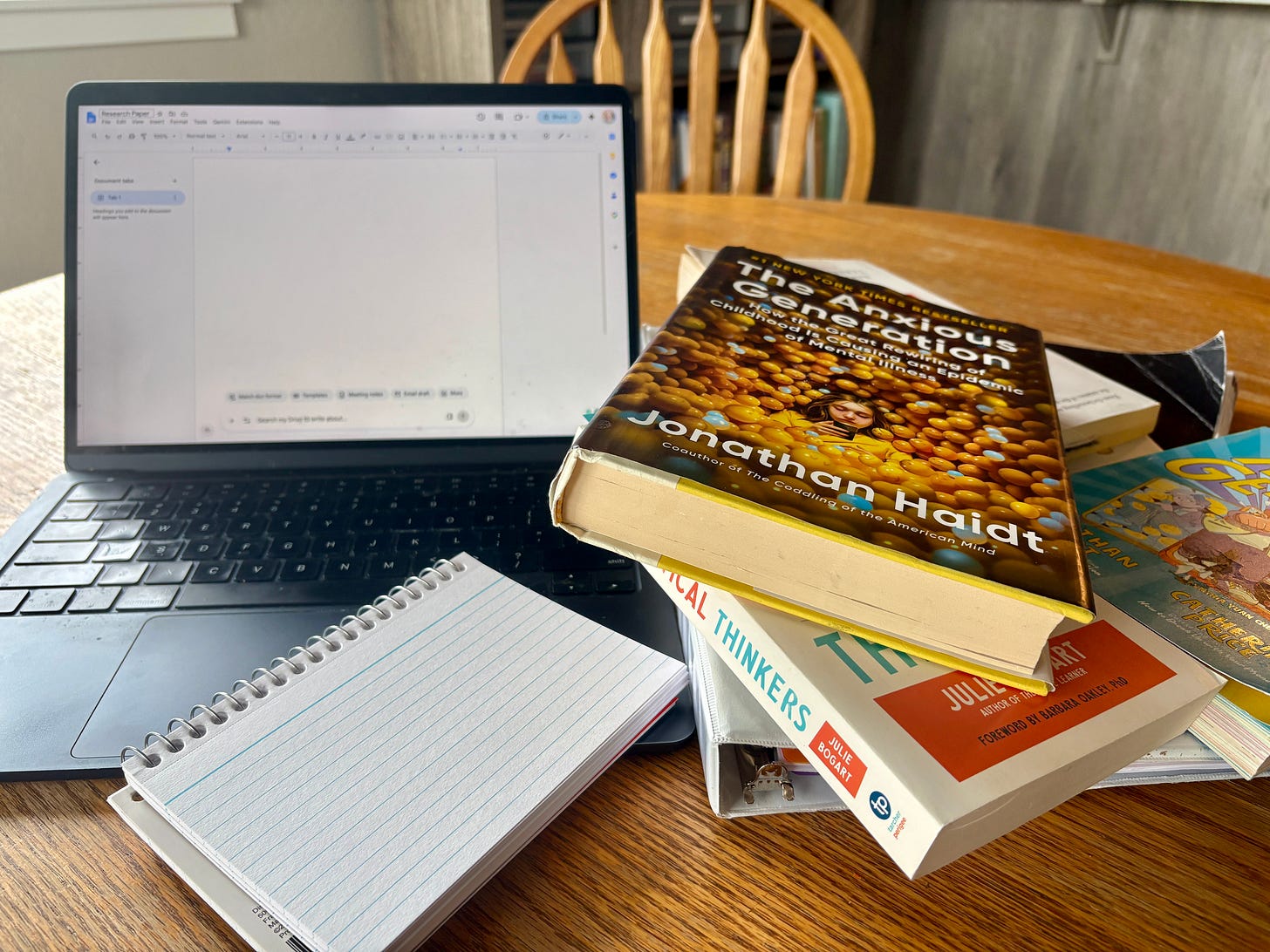 Pile of books and a laptop on a kitchen table. Pile of books and a laptop on a kitchen table.