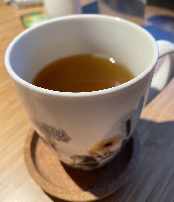 Left: A small pot with garlic, ginger slices, and turmeric slices being brought to a boil. Right: A cup of green tea infused with cayenne powder and the ginger/turmeric water from the pot on the left.