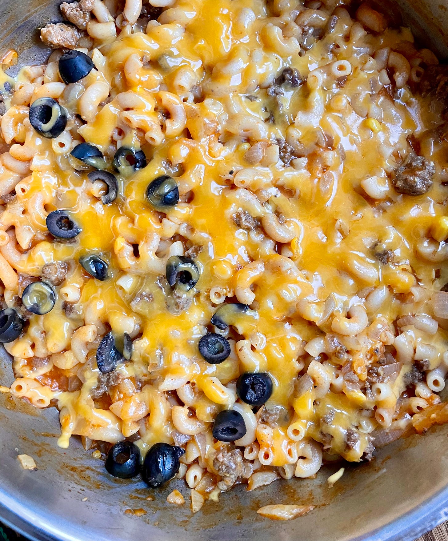 glistening pan of goulash with orange melted cheese and black olives on top