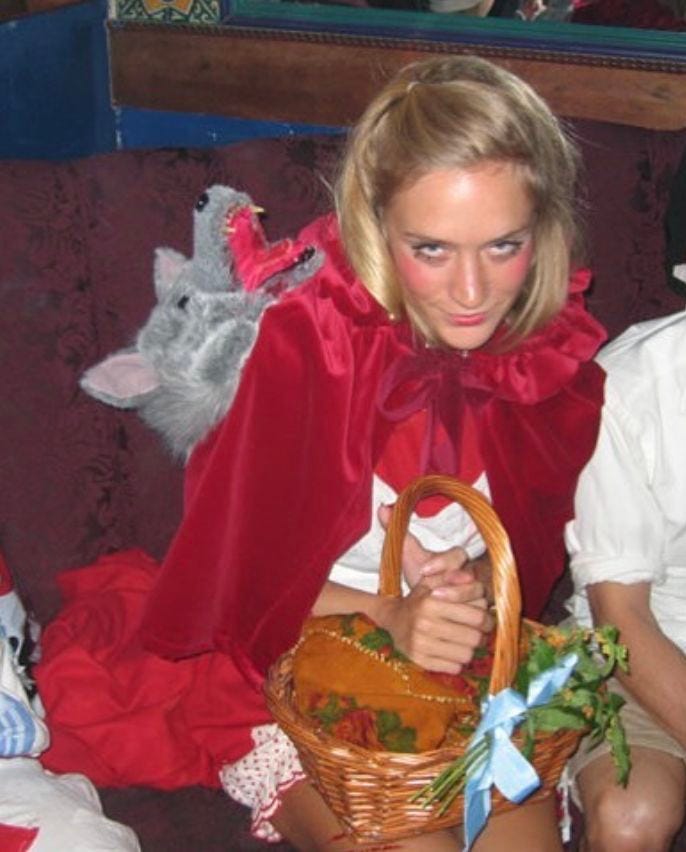 This may contain: two people sitting on a couch with one holding a basket and the other wearing a red cape