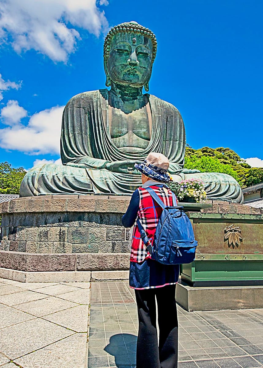 Woman with back to camera standing before huge weathered status Woman with back to camera standing before huge weathered status
