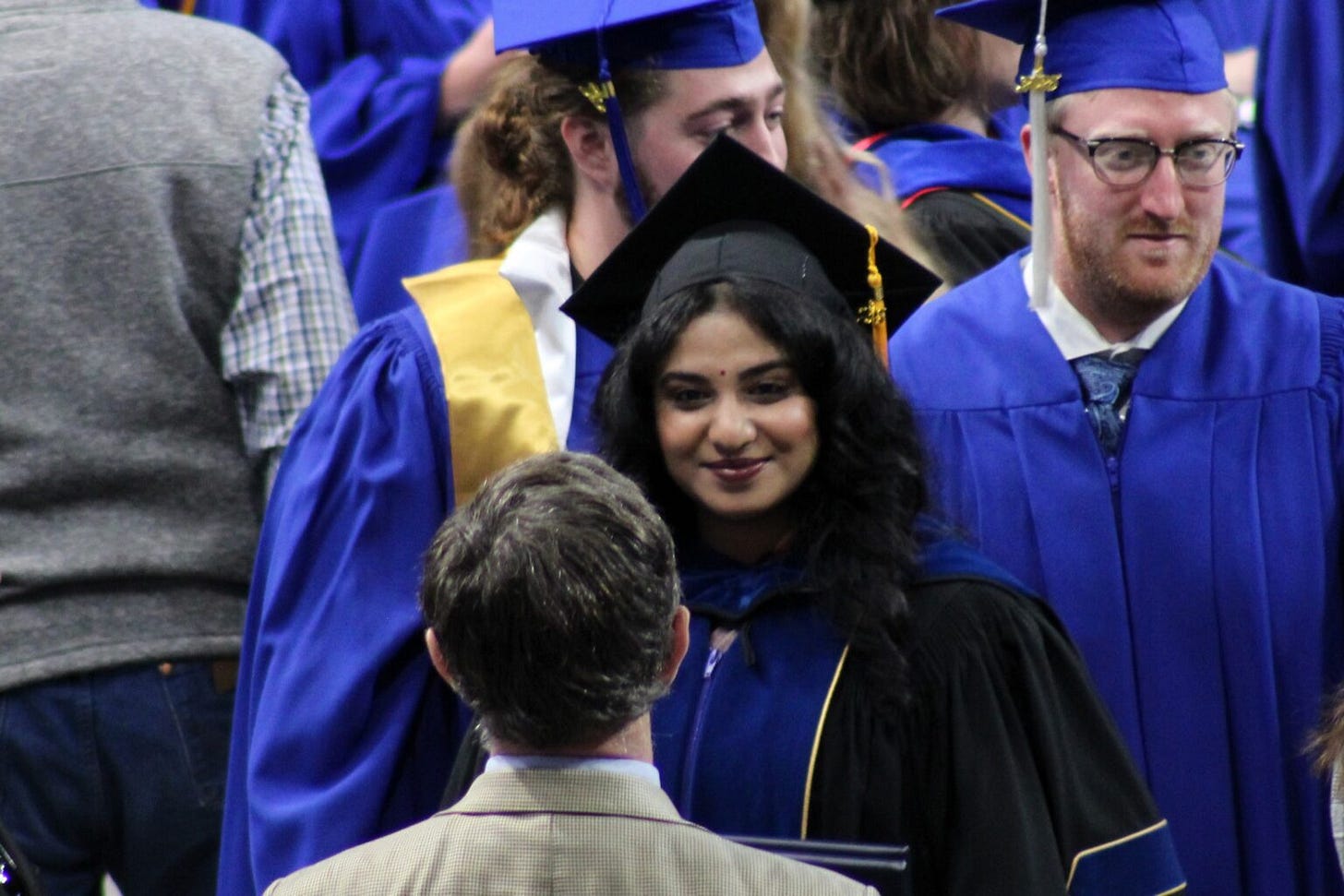 Priya Saxena, center, receives congratulations from her attorney, Jim Leach, foreground, after graduating with a master's and doctoral degree from South Dakota Mines on May 10, 2025, in Rapid City. (Seth Tupper/South Dakota Searchlight)