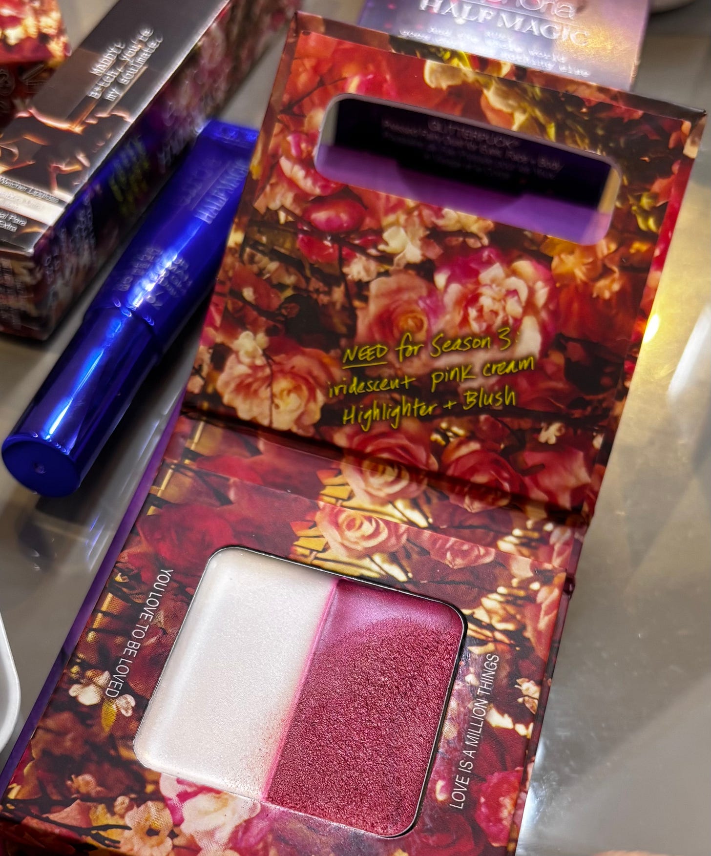 A detail shot of the ‘YOU LOVE TO BE LOVED’ and ‘LOVE IS A MILLION THINGS’ cream blush and highlighter duo in its floral-themed packaging.