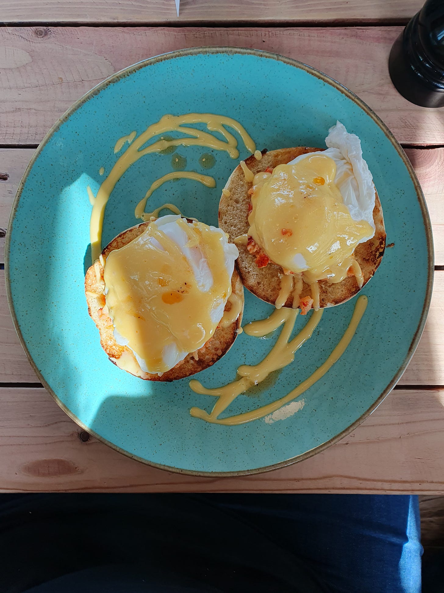 A blue plate with a muffin topped with egg and lobster benedict.