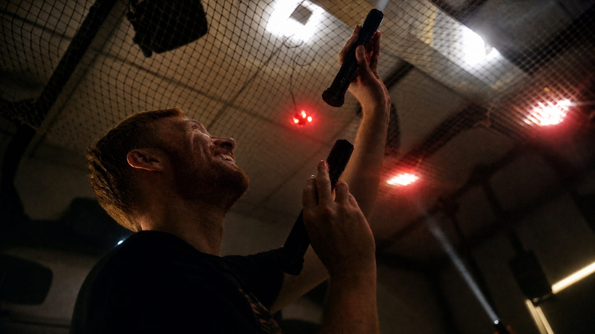 A laughing visitor in silhouette raises two flashlights toward a net of red LEDs overhead A laughing visitor in silhouette raises two flashlights toward a net of red LEDs overhead