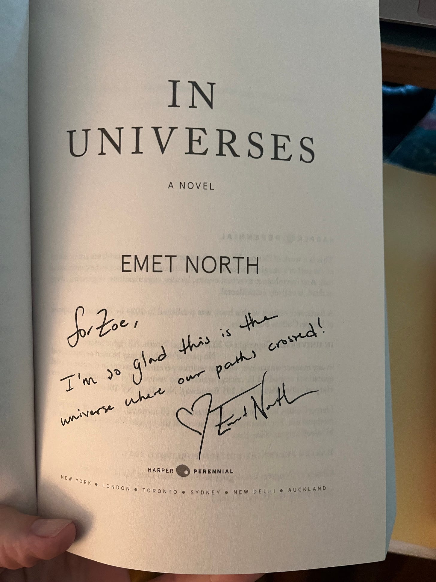 The title page of In Universes by Emet North with the inscription, "for Zoe, I'm so glad this is the universe where our paths crossed! <3Emet North"