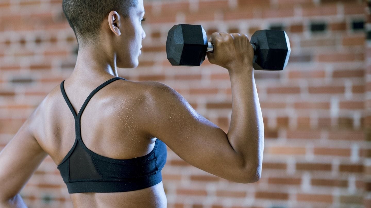 A woman lifting dumbbells during a strength-training workout, focusing on muscle development and overall fitness. A woman lifting dumbbells during a strength-training workout, focusing on muscle development and overall fitness.