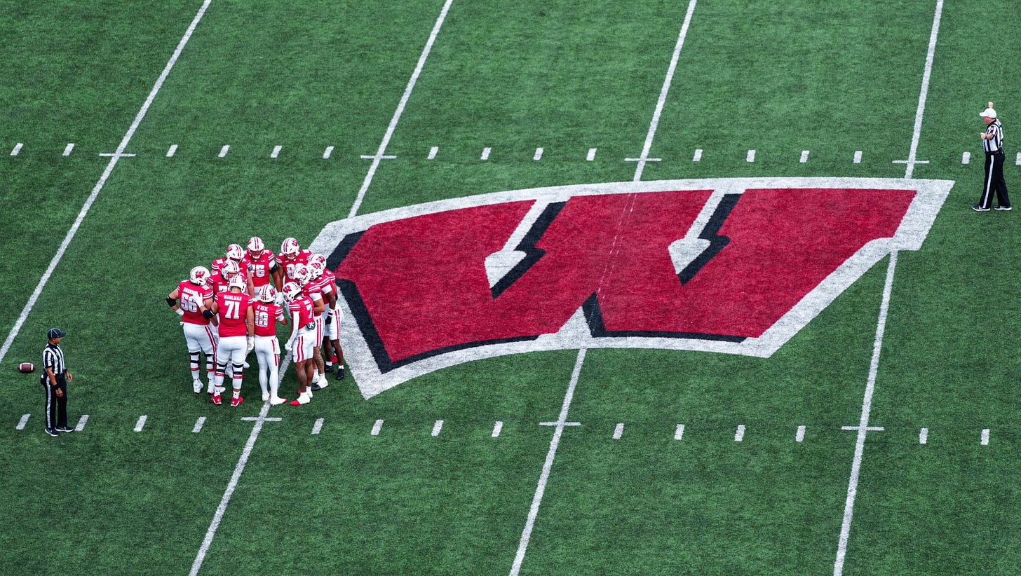 Wisconsin Badgers offense gathers in a huddle at midfield during a game at Camp Randall Stadium. Wisconsin Badgers offense gathers in a huddle at midfield during a game at Camp Randall Stadium.