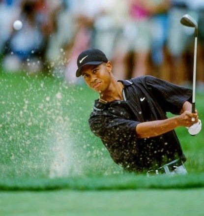 This may contain: a man hitting out of a green golf hole This may contain: a man hitting out of a green golf hole