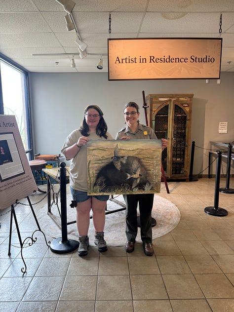 a rock cabin at Carlsbad Caverns artist residency, Bats circling the moon painting, and Ayla Yarborough and a National Park Ranger holding her painting at the NPS studio