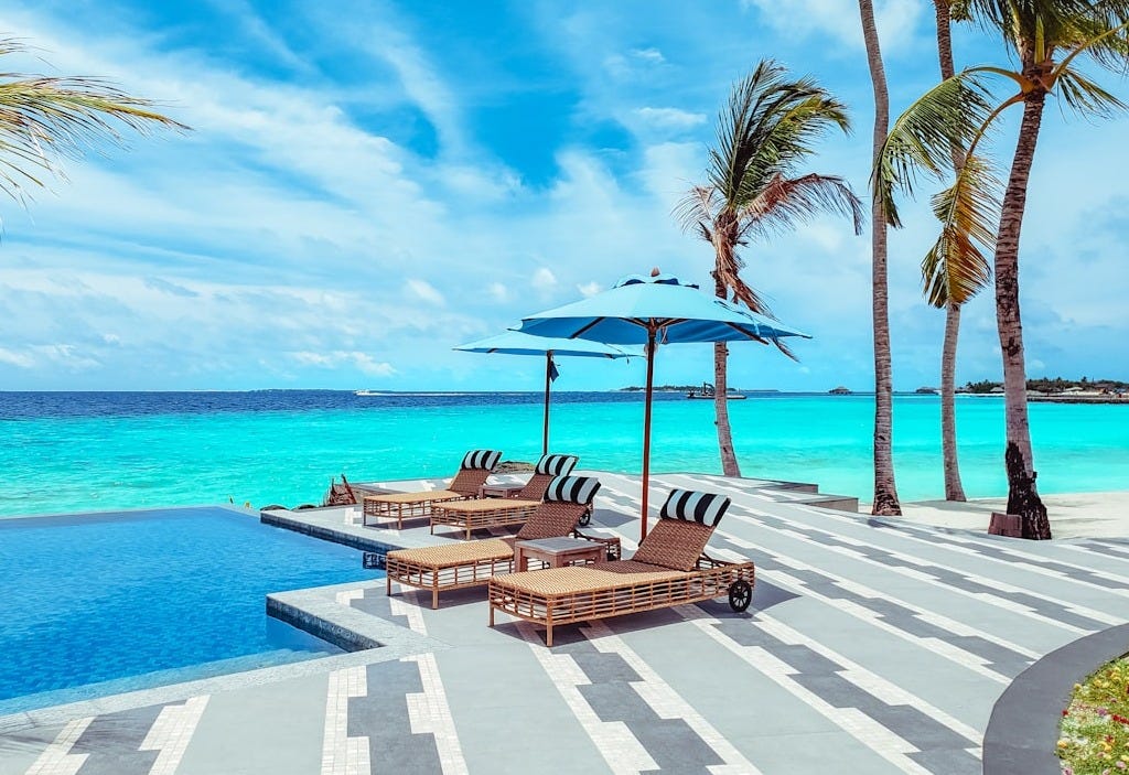 brown wooden lounge chairs on beach during daytime brown wooden lounge chairs on beach during daytime
