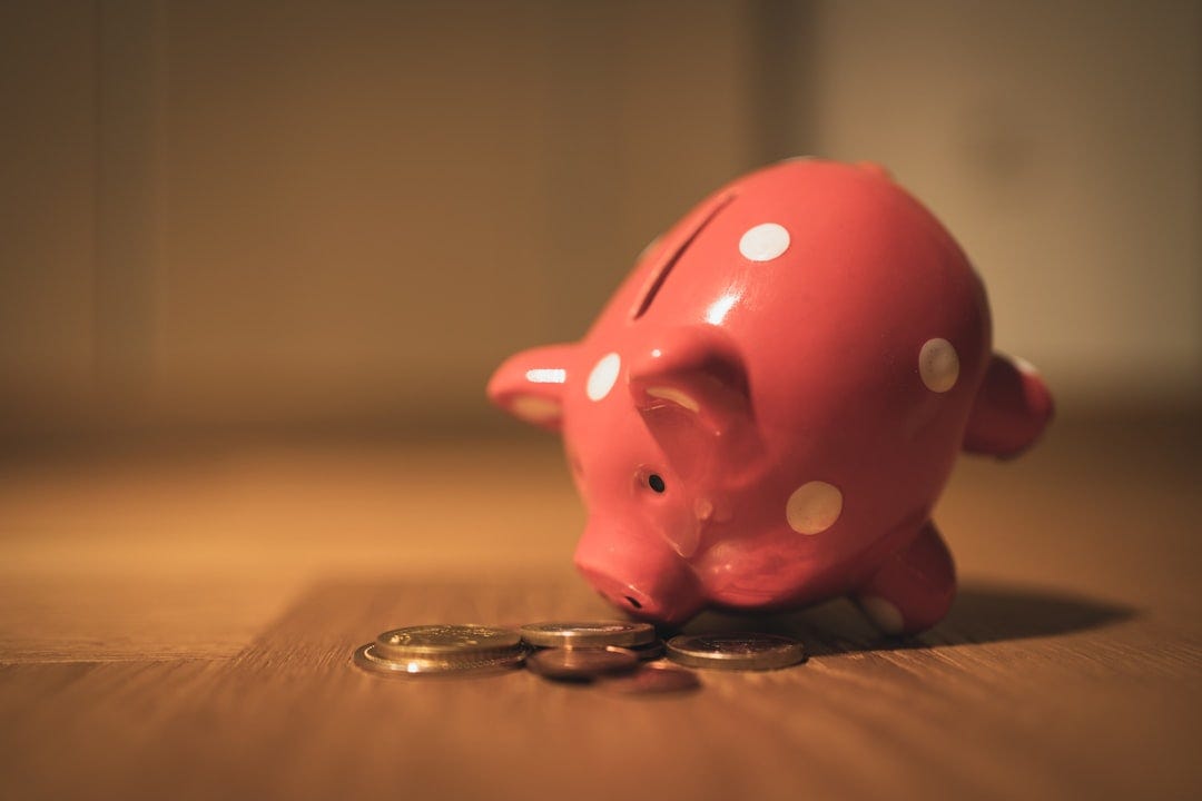 pink pig coin bank on brown wooden table pink pig coin bank on brown wooden table