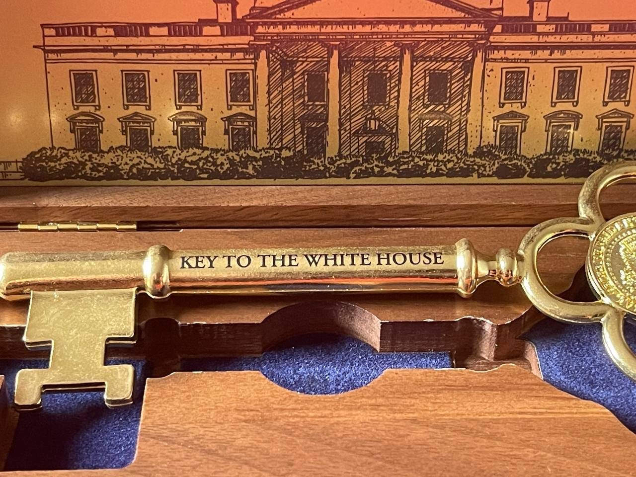The key close-up: “KEY TO THE WHITE HOUSE,” with the White House etching behind The key close-up: “KEY TO THE WHITE HOUSE,” with the White House etching behind