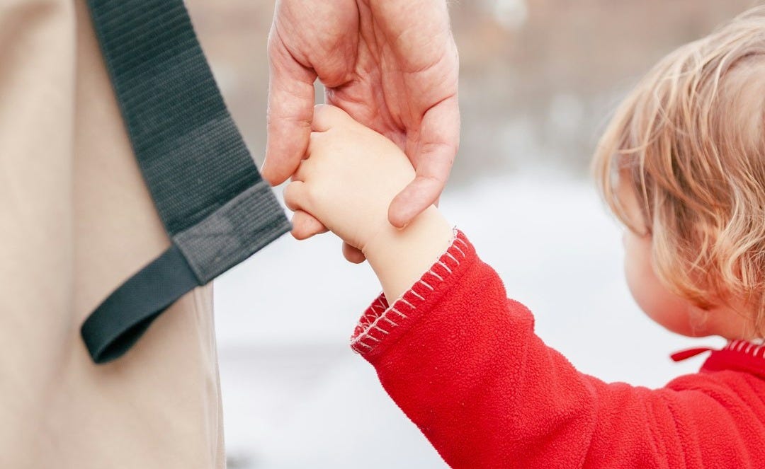 a man holding the hand of a small child