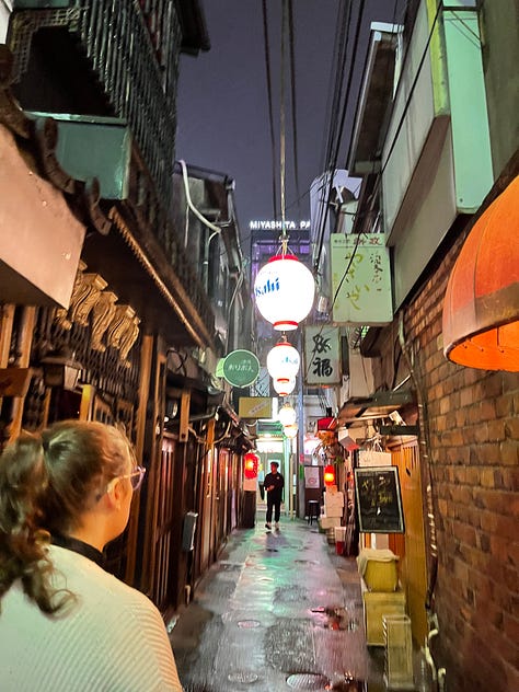 A collage of nine photos from travels in Japan: two sumo wrestlers posing with visitors; vintage kabuki posters on display; a small group sitting on tatami mats during a cultural workshop; a mannequin dressed in a traditional kimono with floral patterns; three people smiling in front of a lantern-filled temple gate; a night market vendor grilling skewers and takoyaki; two friends taking a selfie in Shibuya among bright city signs; the waterfront skyline and Ferris wheel in Yokohama; and a narrow alleyway in Kyoto lined with glowing izakaya lanterns.