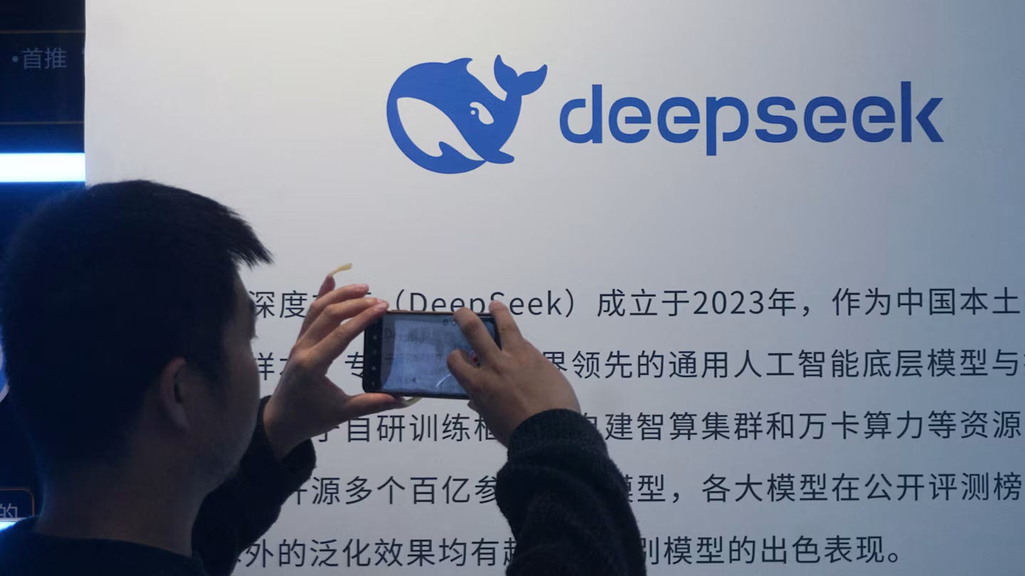 A man takes a photo of a DeepSeek display featuring the company's blue whale logo and Chinese text about its AI model.