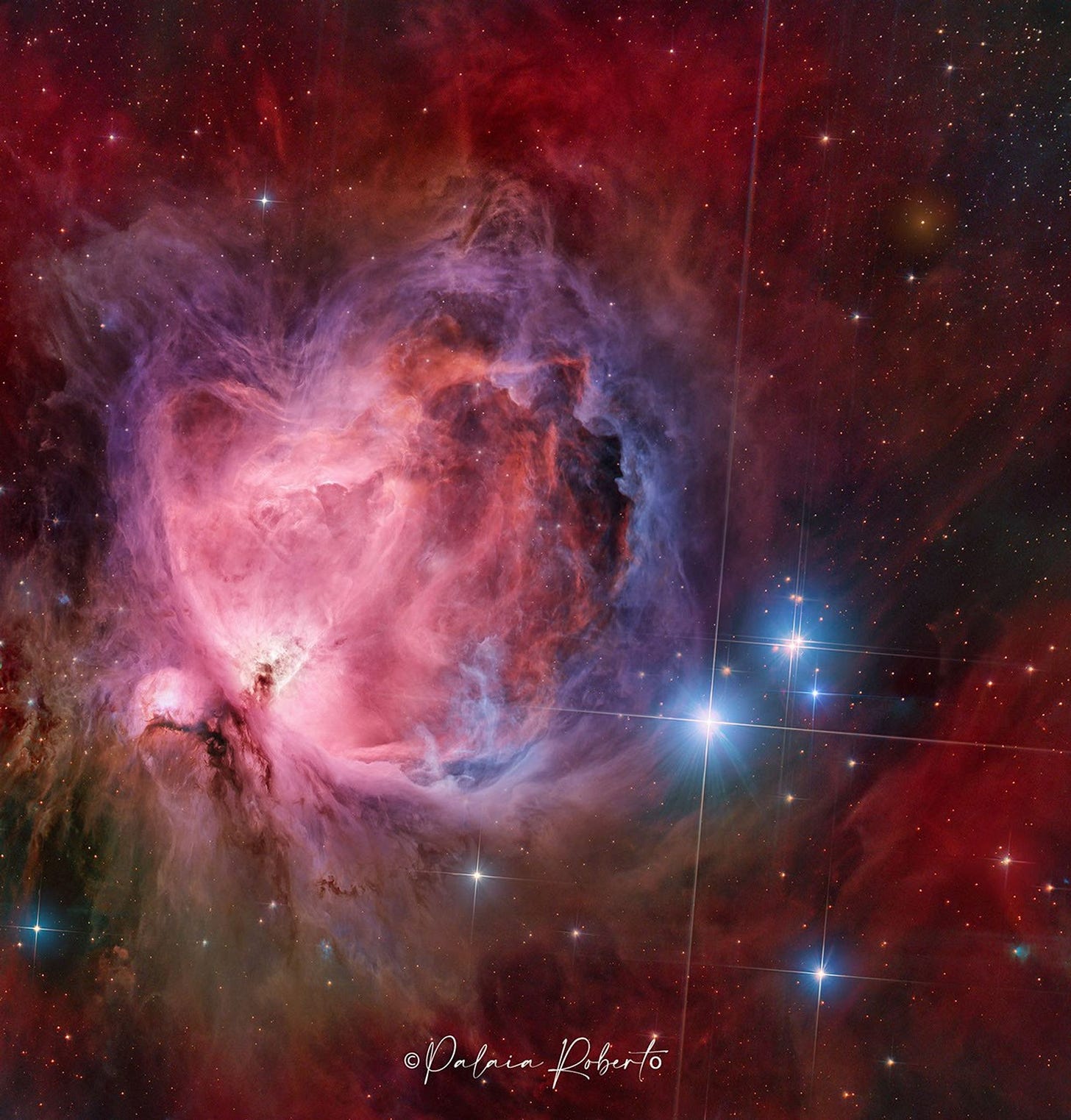A starfield features a large and colorful nebula in its center, filled with dark dust and glowing gas in red and blue. A starfield features a large and colorful nebula in its center, filled with dark dust and glowing gas in red and blue.