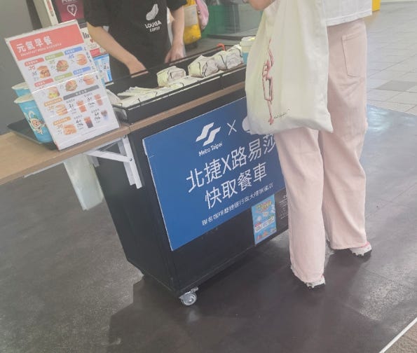 Think with your customer: temporary rush hour coffee pickup. The stand says: Metro Taipei × Louisa Coffee quick pickup cart