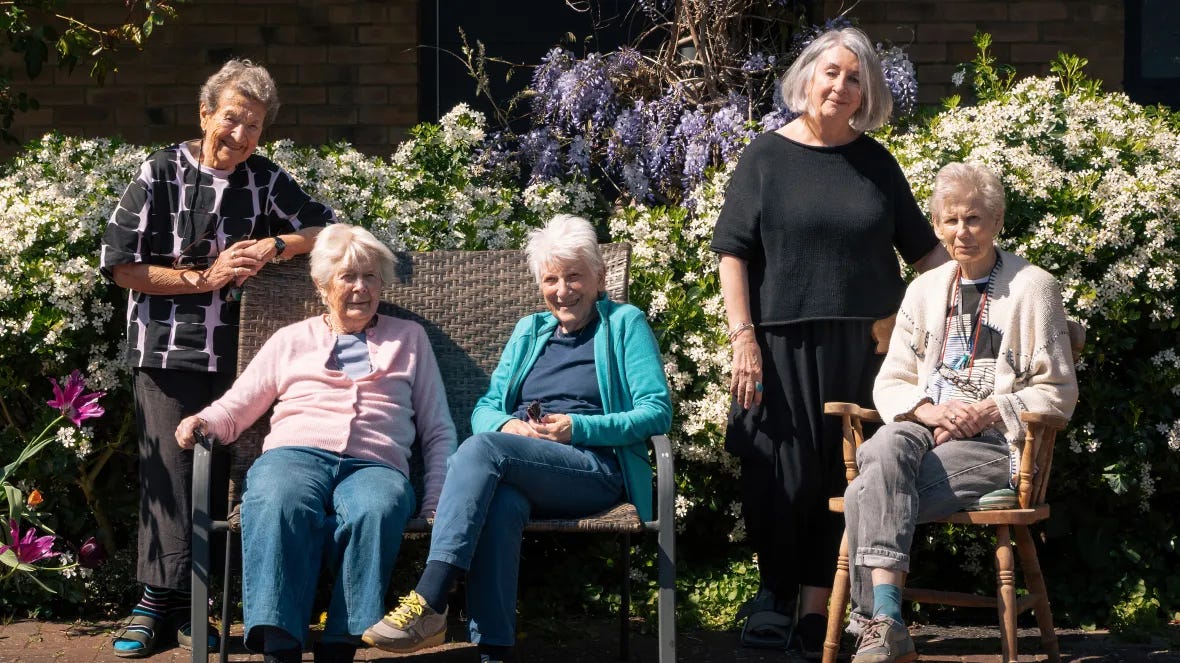 Five women from the New Ground Housing Project smile for a photo in a garden.