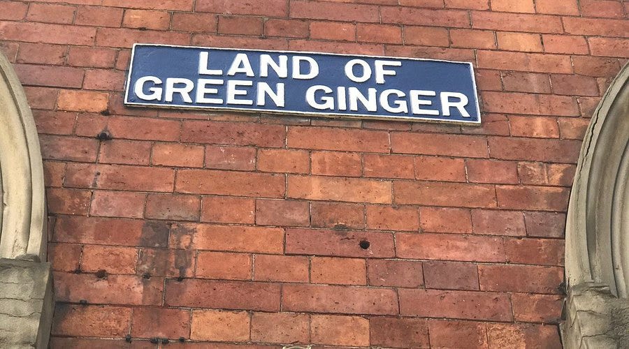Blue street sign with white writing in capital letters "Land of Green Ginger", on red brick wall.