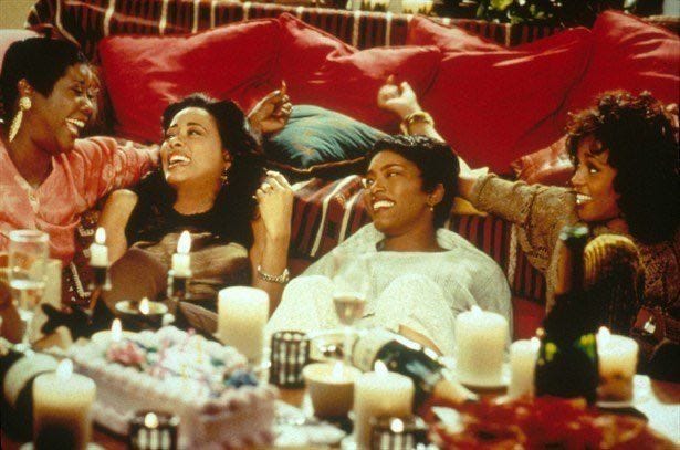 This may contain: group of people sitting around a table with candles and cake in front of them on the couch