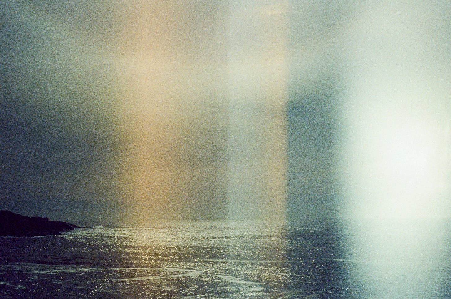 A film photograph of the ocean and the sky, with multiple light leaks.