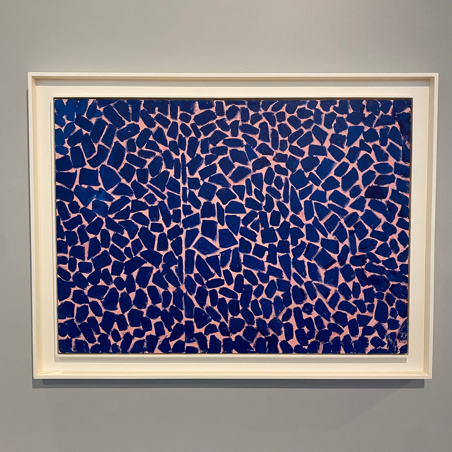 Abstract painting of blue mosaic-tile-like-shapes on a pinkish background.