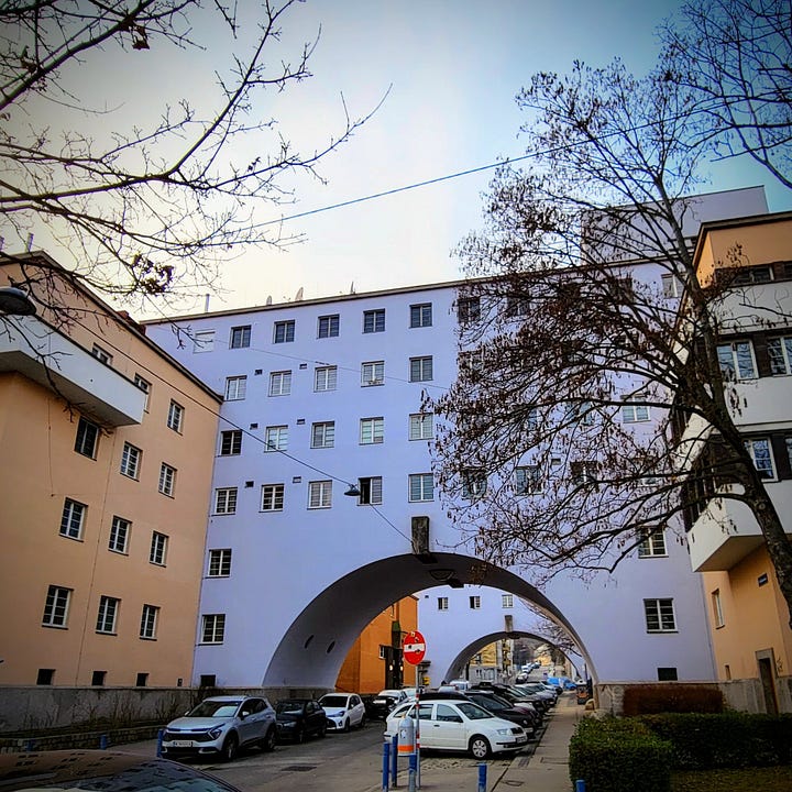 Two photos of the exterior of a large apartment block. The second photo depicts the main entrance to the interior courtyard.