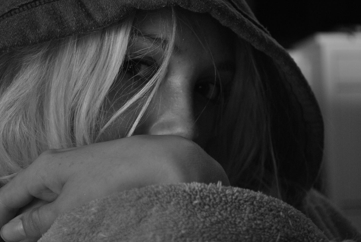 A woman hides beneath the heavy hood of a jacket and stares at the camera. A woman hides beneath the heavy hood of a jacket and stares at the camera.