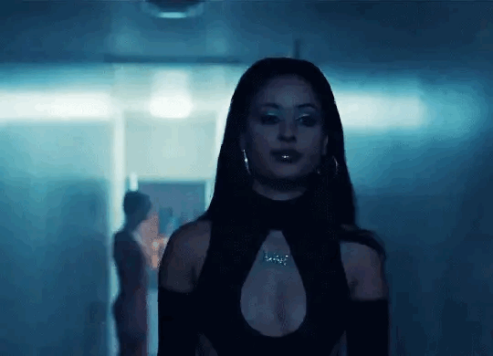 This may contain: a woman standing in a dark room with her back to the camera