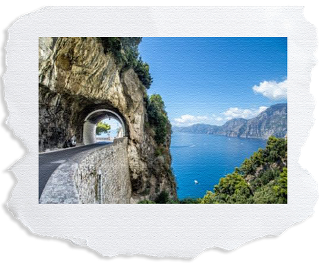 Six images of Italy. Image one a table set looking out onto the city. A cat peeping over some rocks, a highway that overlooks blue ocean, a shot of the coast with house built up on hits overlooking ocean, an old bright red fiat and lemon tree that looks over the beach.
