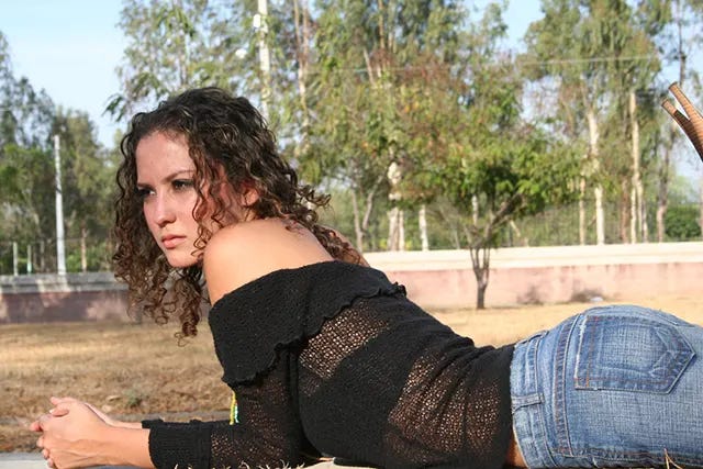 A girl with curly brown hair wearing an off-the-shoulder top, a stylish carryover that remained popular through the early 2000s. A girl with curly brown hair wearing an off-the-shoulder top, a stylish carryover that remained popular through the early 2000s.