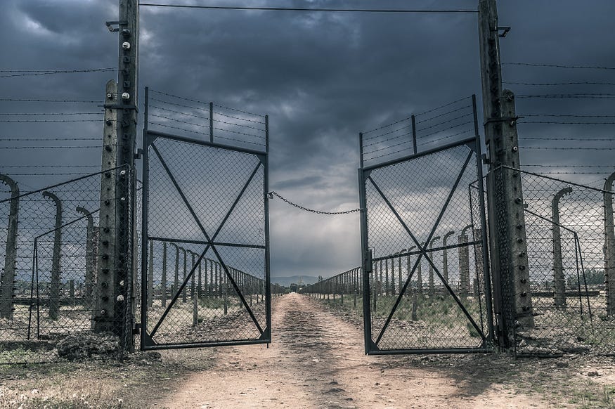 Large steel gates leading to a dirt track