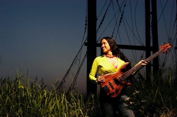 Maximina Juson holding her bass guitar.